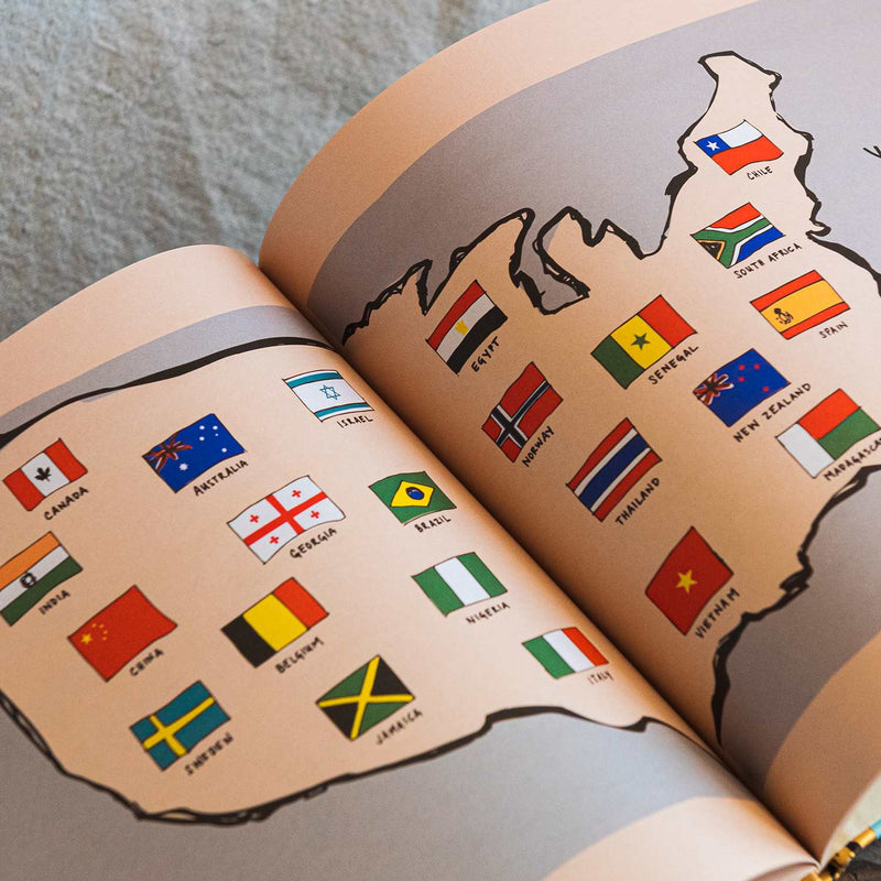 john wayne the hyphen book opened to pages of U.S. map with different countries flags 
