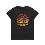 front of womens black t-shirt with "looks like its gonna be another fine day john wayne" in orange and yellow font on it