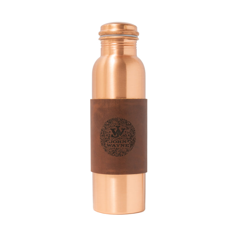 copper bottle with leather sleeve that has JW and flower like design around it 