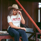 woman sitting and wearing white womans tee with "john wayne my kind of american" in red