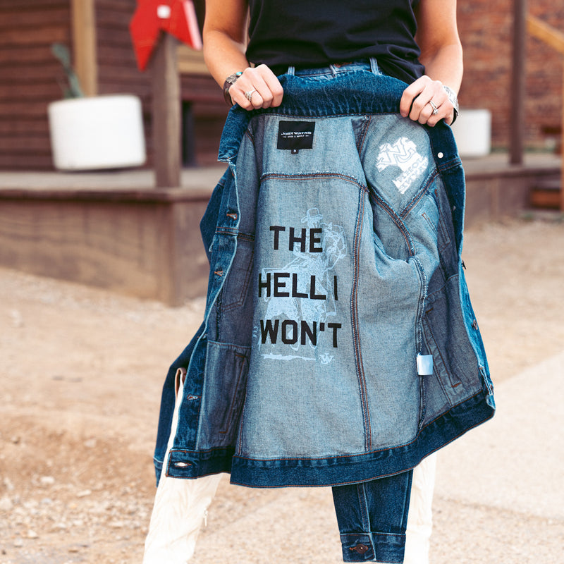 woman opening denim jacket with inside saying "the hell I won't"