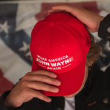 man putting on red make america john wayne again hat
